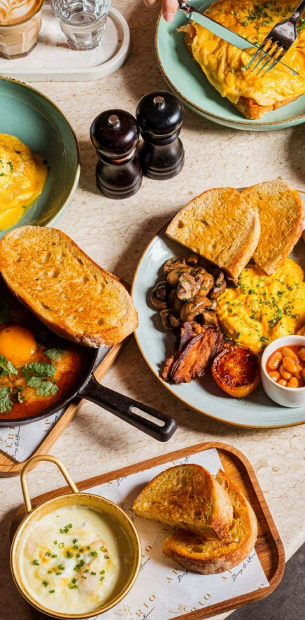 A luxury hotel breakfast spread features toast, creamy scrambled eggs, mushrooms, and savory sides, highlighting fine di